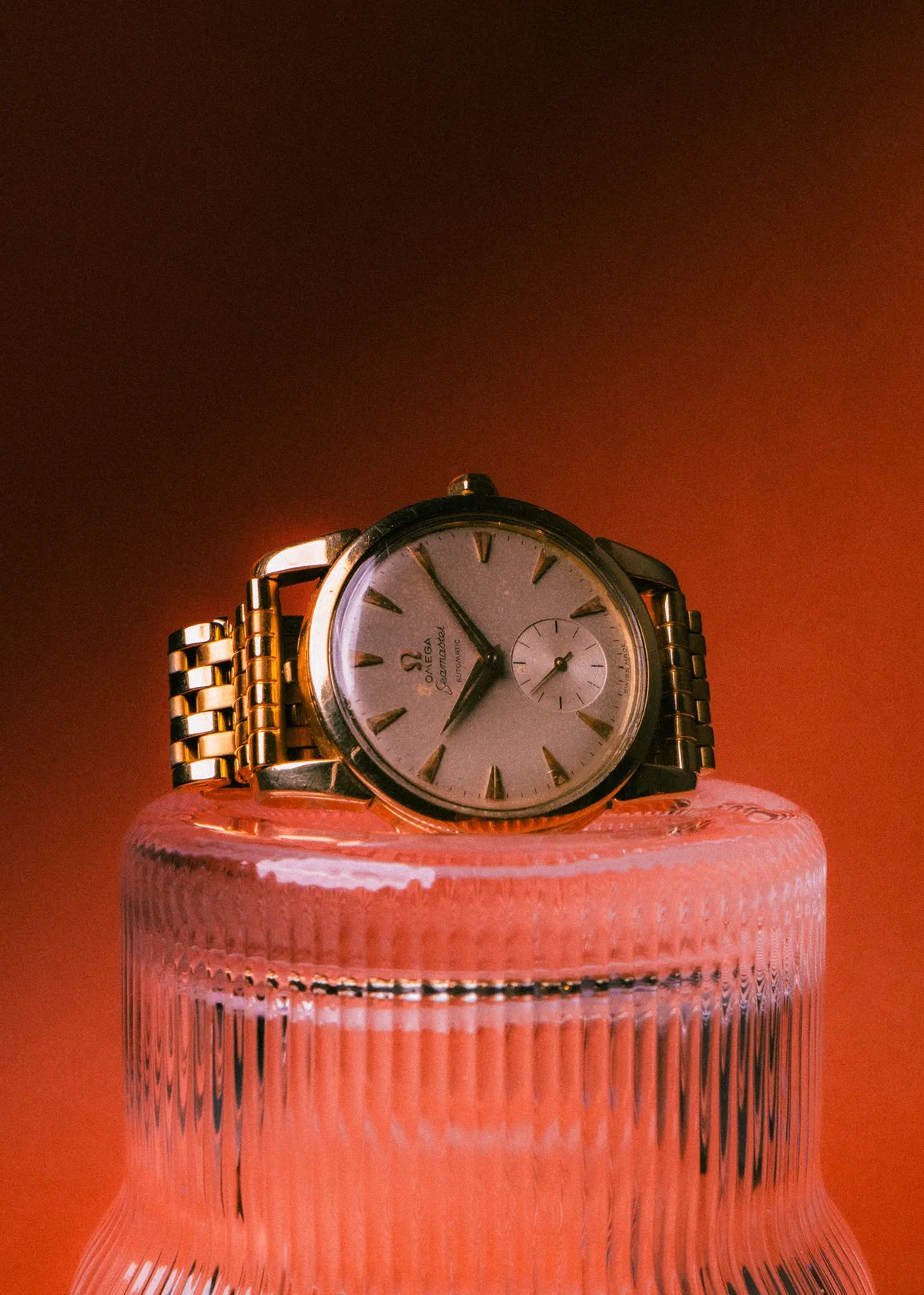 Reloj Omega Seamaster dorado sobre base de vidrio