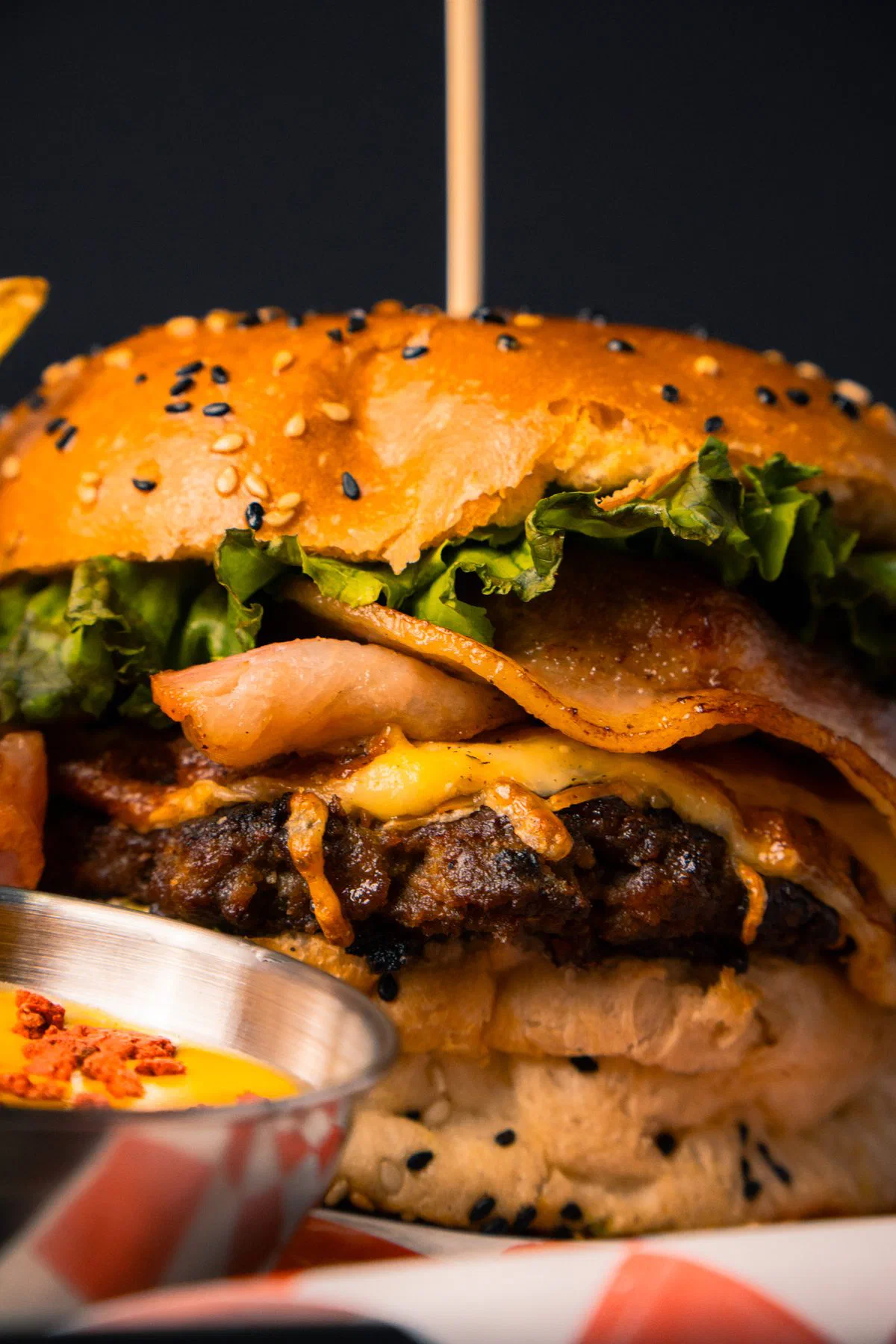 Primer plano de hamburguesa de Rossie's Burger con tocino, queso y aderezo picante